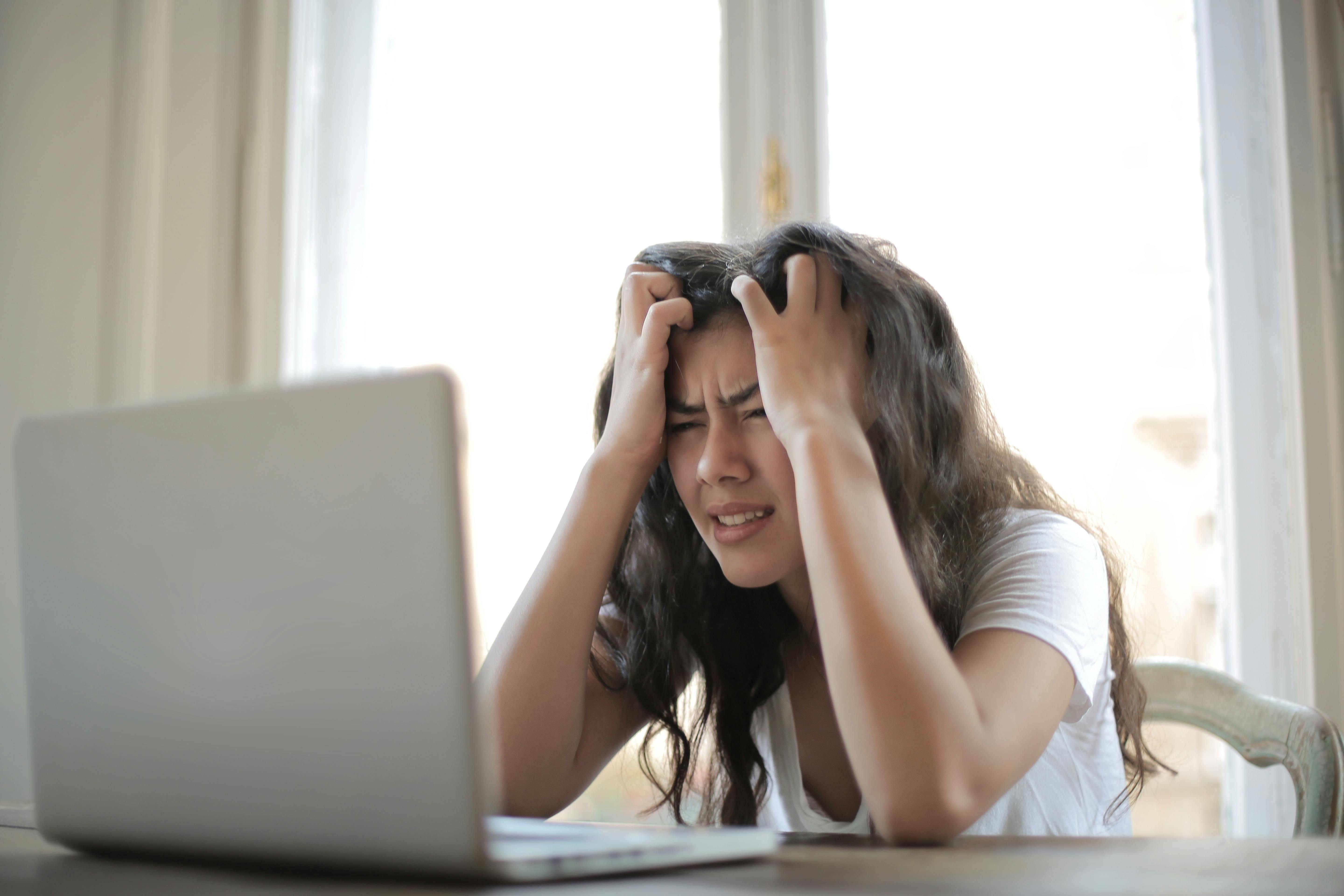 Photo of a woman sitting in front of laptop looking desperate